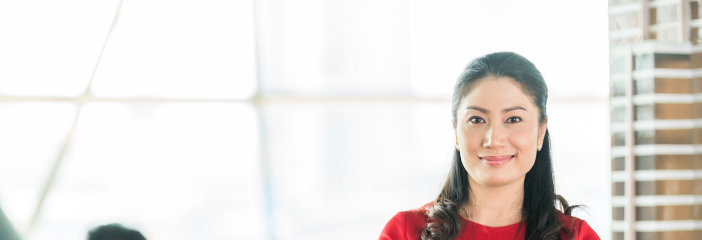 Asian woman standing in meeting room with crossed arms